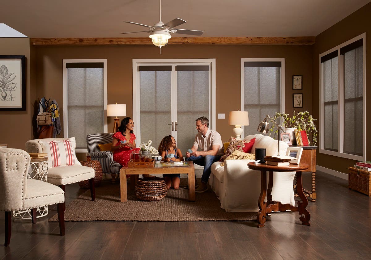 Family of three sitting in living room with remote controlled roller shades